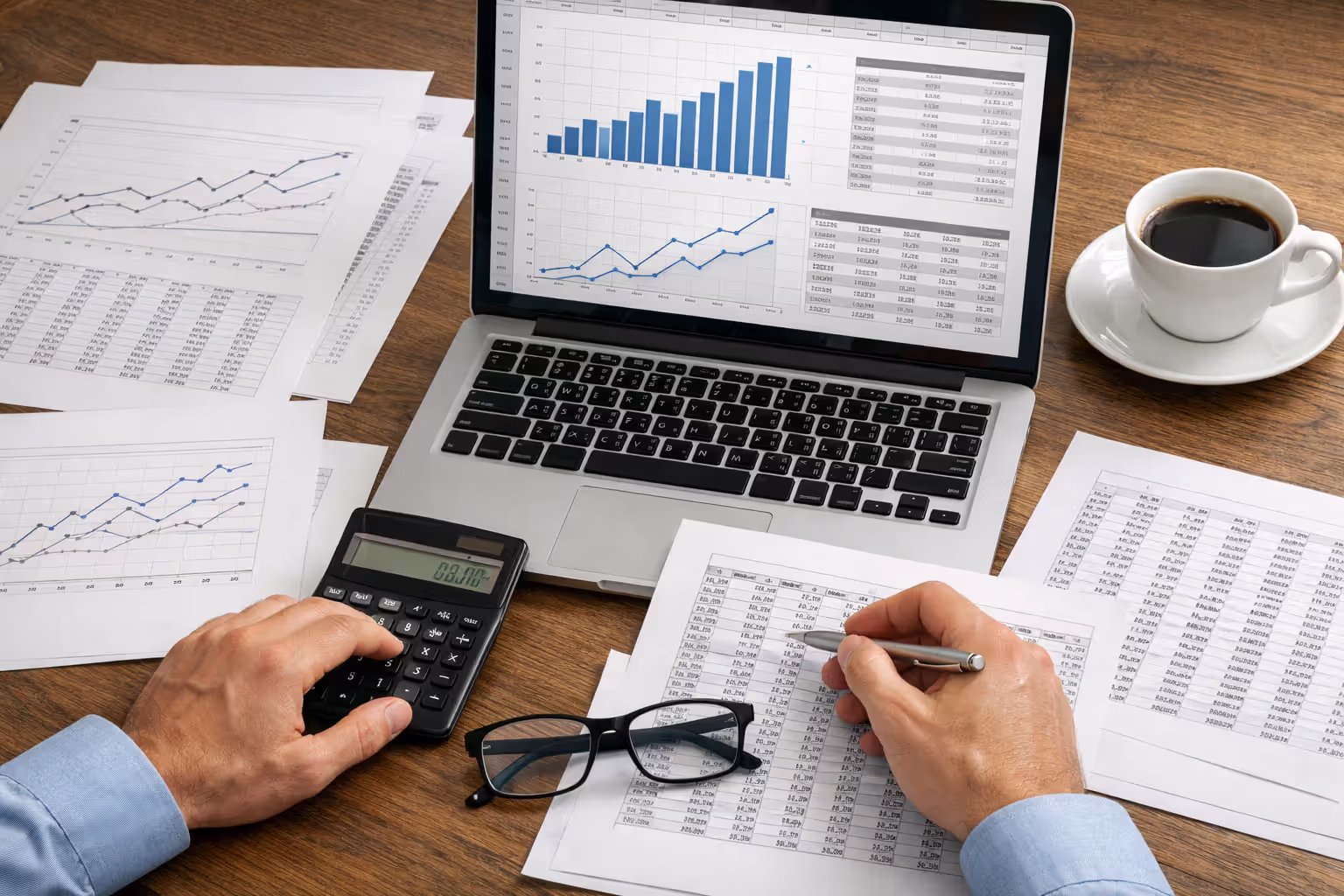 Economic expert workspace with laptop showing earnings projection charts, actuarial tables, and financial documents