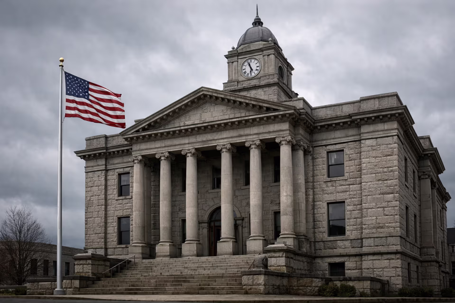 West Virginia stone courthouse with columns and American flag under overcast sky